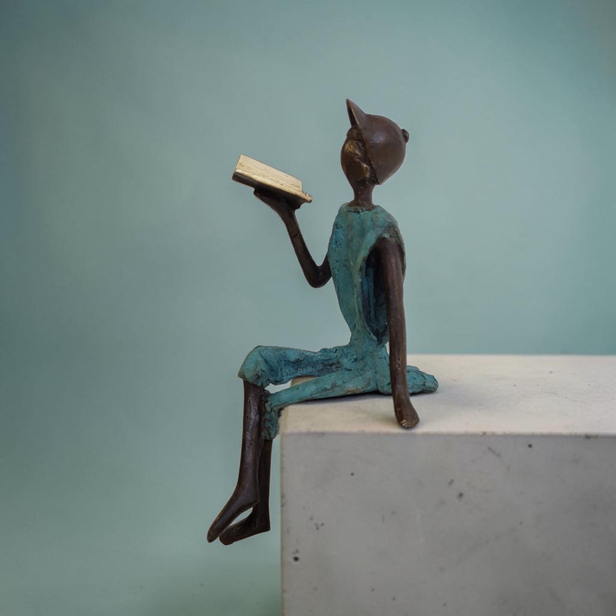 Bronze-Skulptur "Yohann" Enfant avec livre et casquette | by Souleymane