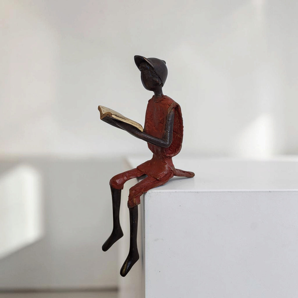 Bronze-Skulptur "Hugo" Enfant avec livre et casquette | by Souleymane