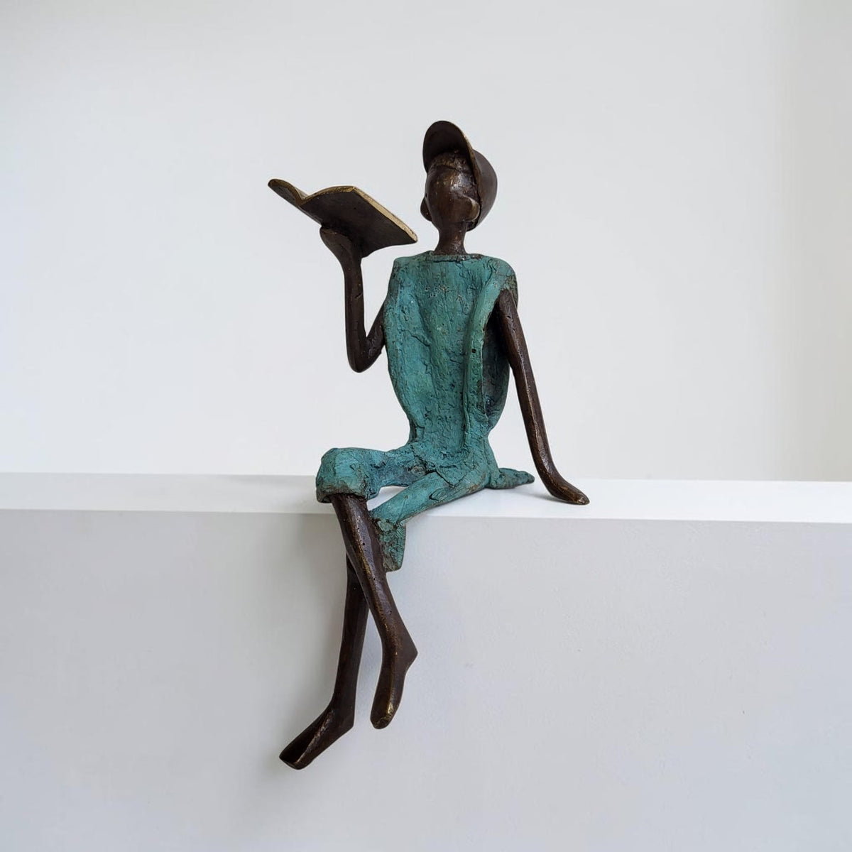 Bronze-Skulptur "Yohann" Enfant avec livre et casquette | by Souleymane
