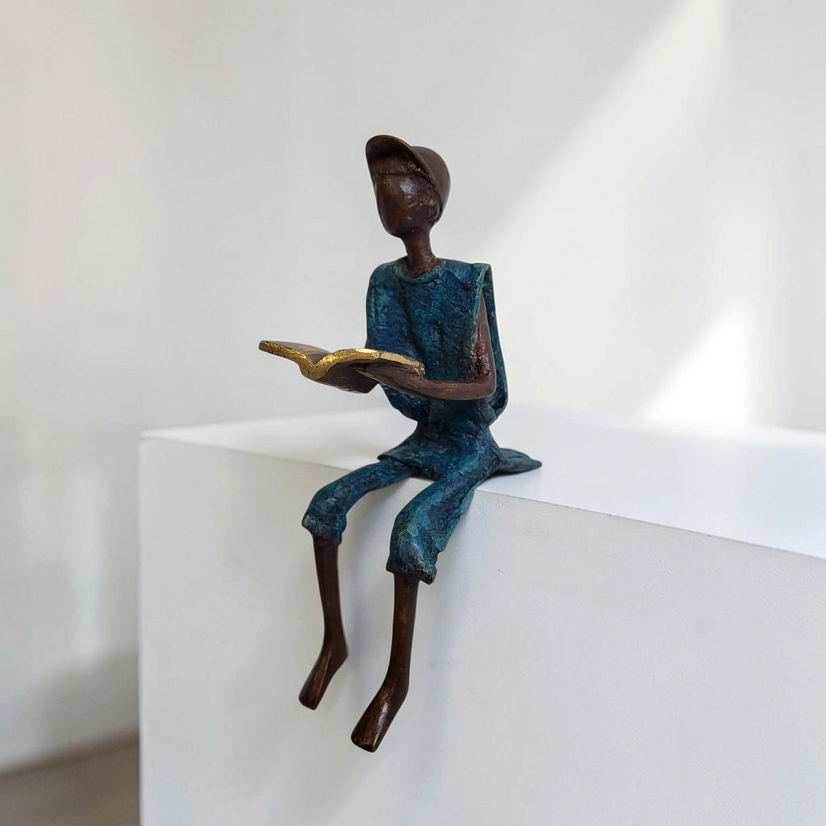 Bronze-Skulptur "Hugo" Enfant avec livre et casquette | by Souleymane