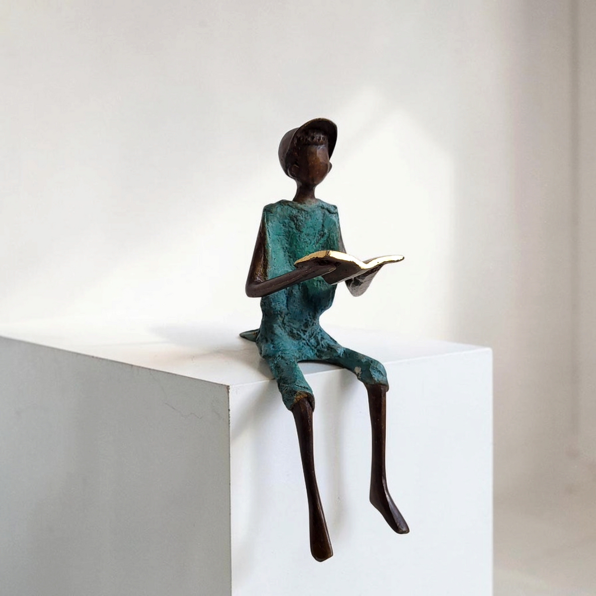 Bronze-Skulptur "Hugo" Enfant avec livre et casquette | by Souleymane