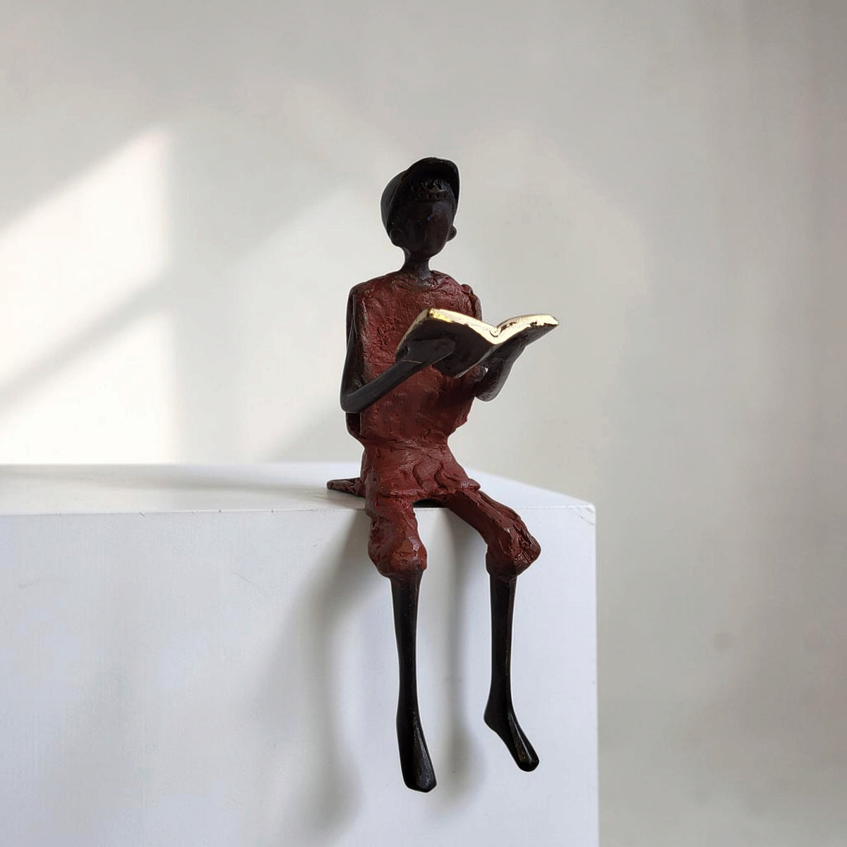 Bronze-Skulptur "Hugo" Enfant avec livre et casquette | by Souleymane